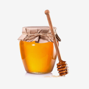 A Glass Jar Of Honey With Dipper Resting On Top Surrounded